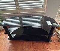 Overall view of black glass TV stand showing three surfaces