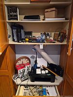 Overview of cabinet showing printer, phones, lamp, clock and various office supplies