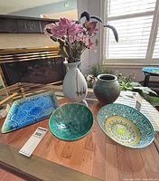 Group shot of five ceramic items: platter, two bowls, pitcher with flowers, and vase