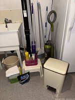 Group shot showing garbage can, vacuum, brooms, mops, stool, bucket, cleaning supplies