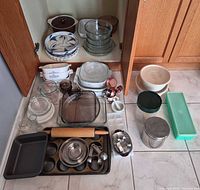 Overall lot showing cookware, bakeware, mixing bowls, pans, rolling pin, measuring tools and storage containers