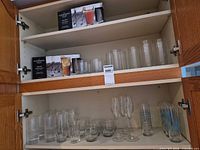Cabinet shelves containing boxed tumbler sets, loose highballs, tumblers and champagne flutes