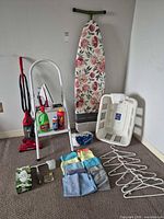 Group shot of all items in lot: ironing board, ladder, vacuum, hamper, iron, cleaning supplies, hangers, cloths