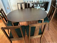 Oval wood dining table with six chairs all around
