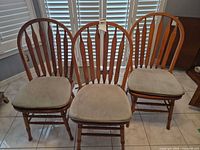 Front view of three Windsor chairs with cushions