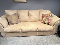 front view of beige three-seater sofa with two throw cushions
