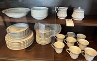 Overall cabinet view showing stacks of plates, bowls, eight teacups, creamer and sugar bowl for count and pattern confirmation
