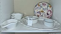 Shelf view: large oval platter, nested bowls, floral bowl, stack of small pour-spout bowls, ramekin