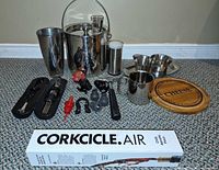All items arranged: ice bucket, shaker, pint glass, small pitchers, mug, cheese board, trays, Corkcicle box, bar tools