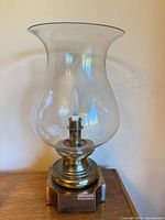Lantern assembled showing brass base, clear glass hurricane shade, bulb visible
