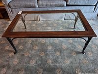 Full view of rectangular wood-framed glass coffee table in front of sofa