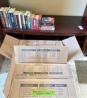 Books aligned on low shelf with moving boxes in foreground
