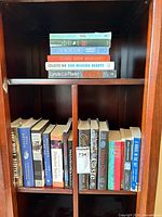 Books on shelf showing hardcovers and paperbacks, spine titles visible