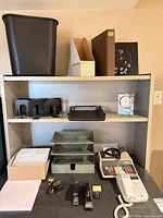 Overall view of shelving with wastebasket, magazine files, binder, clocks, letter holders and trays