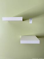Both white floating shelves mounted on wall