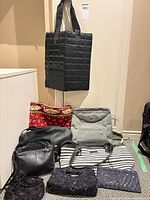 All eight bags arranged together, black woven tote hanging, others on floor