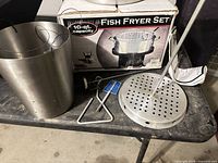 Pot, strainer plate, lift tools, thermometer and box on table