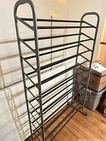 Front view of gray metal 10-tier shoe rack on casters