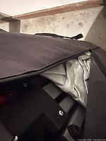 Folded metal canopy frame and fabric top inside black carry bag