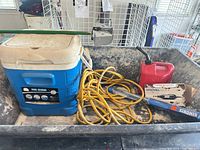 Overall view showing cooler, extension cord, gas can, boxed Dremel tool inside cart