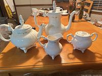 Four-piece bone white china tea service displayed on table