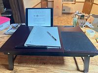 Lap desk with notebook, pen and tablet in slot, legs extended