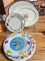 Group shot of five pieces showing both platters, handled plate and two fish dinner plates