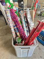 Bin containing multiple Christmas wrapping paper rolls
