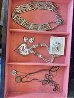 Tray overview showing heart pendant necklace with earrings, unicorn pin, multi-strand bead choker and chain necklace