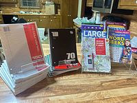 Full lot showing loose-leaf paper packs, spiral notebook stack, planner, puzzle books