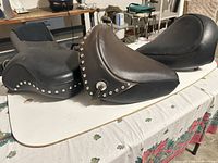 Three motorcycle seats displayed on table