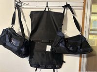Garment bag centered between two duffel bags on wall hook