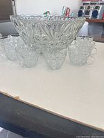 Pressed glass punch bowl with eight cups arranged in front