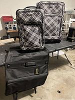 Two plaid Prodigy suitcases and folded garment bag