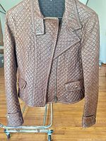 Front view of brown quilted moto jacket showing asymmetrical zipper, snap lapels, quilt pattern