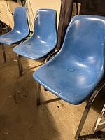 Three blue plastic chairs side by side showing overall style and condition