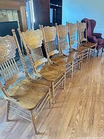 Set of six carved oak dining chairs lined up showing overall form