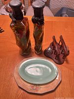 Two filled twisted glass bottles, wood caddy with glass shaker, two platters