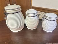 Three white ribbed ceramic canisters with clamp lids