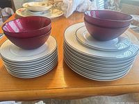 Stacks of dinner and salad plates beside two red bowls