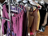Rack showing multiple medium shirts including purple off-shoulder, striped long-sleeve, patterned and yellow tops