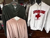 All three hoodies hanging on rack, showing colors and graphic
