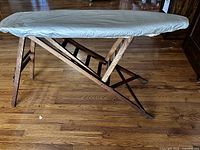Full view of wooden folding ironing board with cover