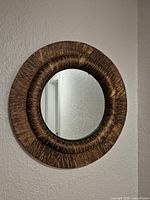 Front view of round wood wall mirror mounted on wall