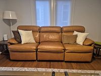 Front view of tan leather 3-seat sofa with four cushions