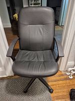 Front view of black faux leather office chair showing seat, backrest and armrests