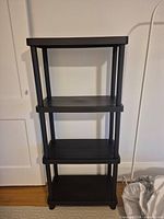 Full view front of black plastic 4-shelf rack