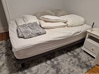 Full view of queen mattress on platform base with bedding