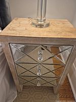 Front and top view showing wood top, mirrored drawer fronts, knobs, wear marks