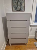 Front view of light gray dresser chest under wall art